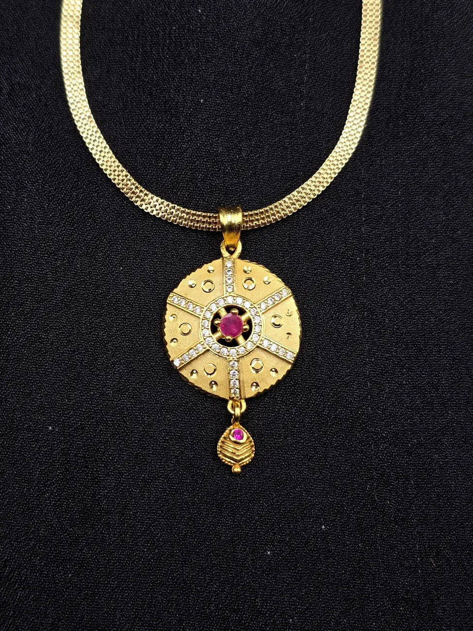 Gold necklace with a decorative pendant on a black background