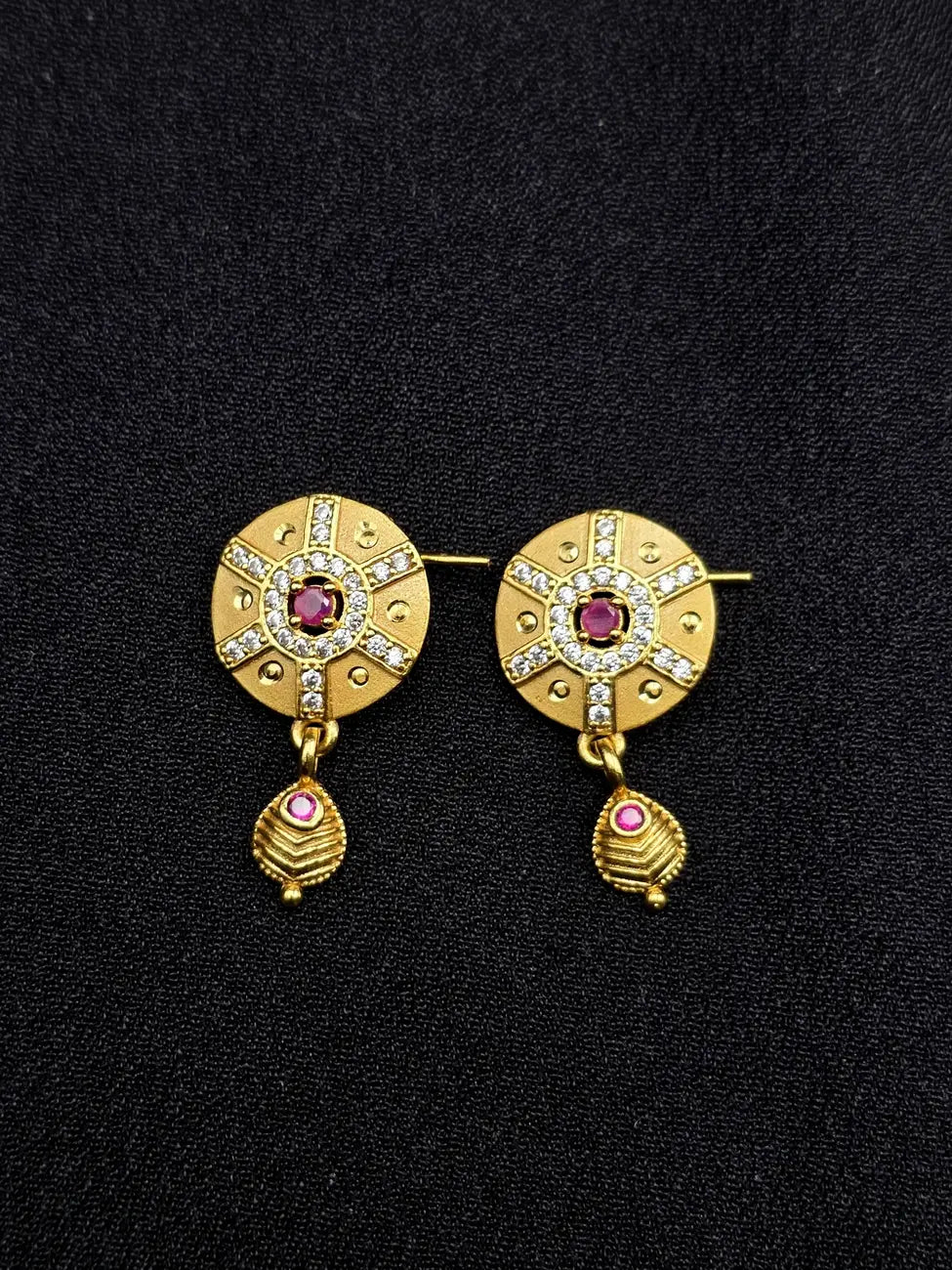 Pair of gold earrings with gemstones on a black background