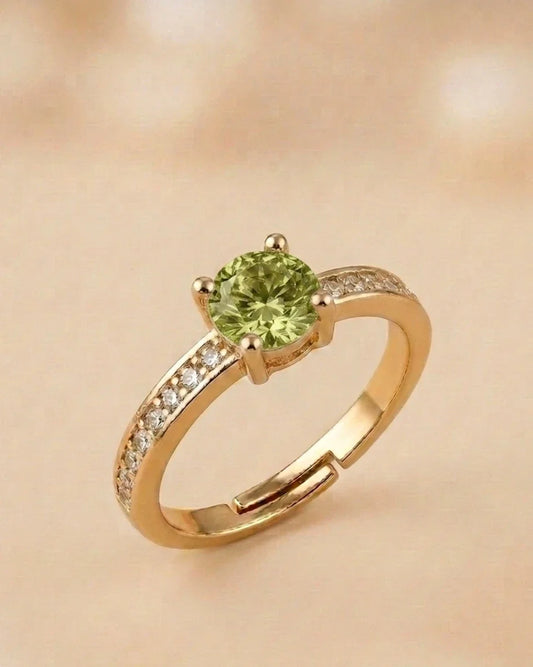 Gold ring with a green gemstone on a beige background