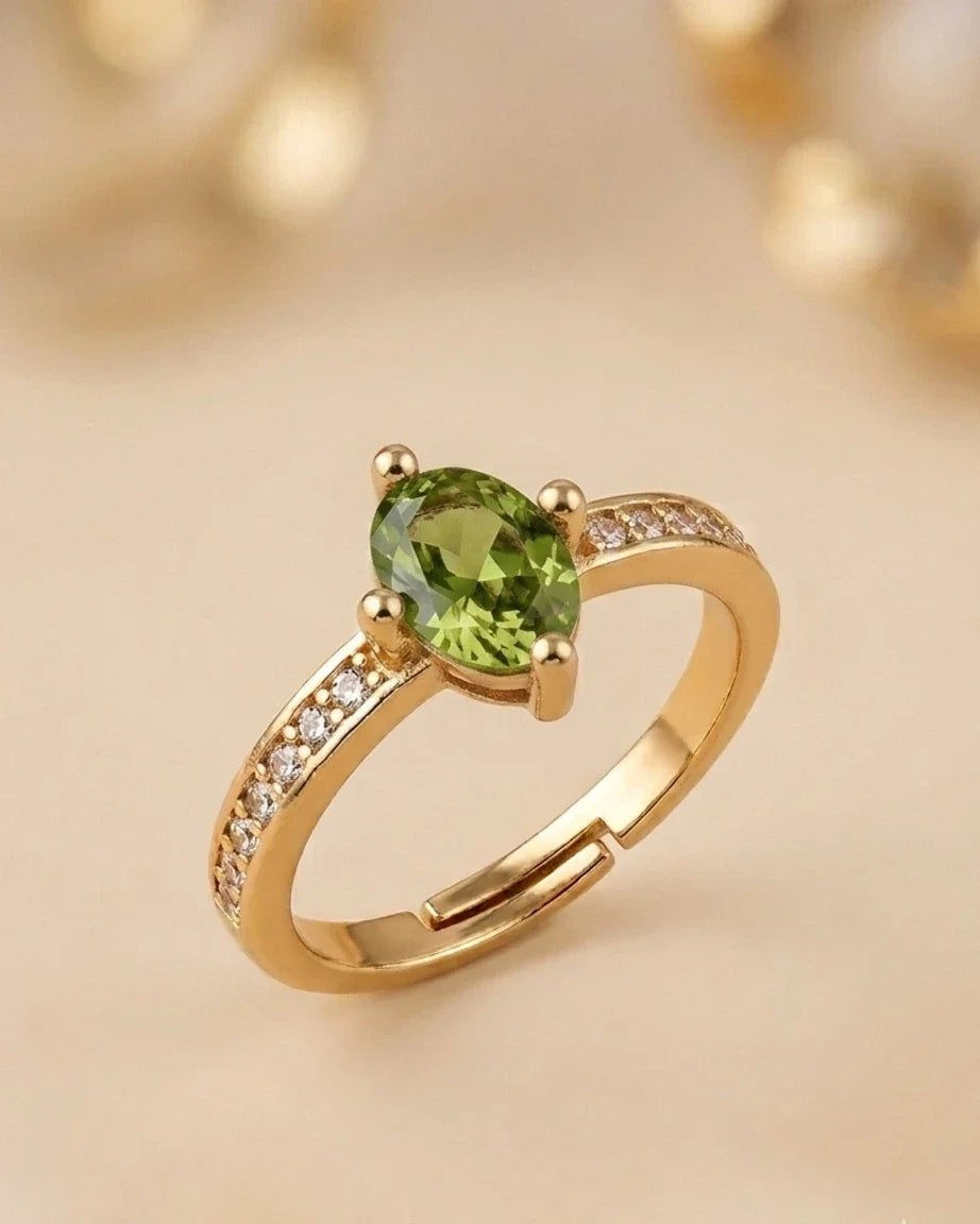 Gold ring with a green gemstone on a beige background