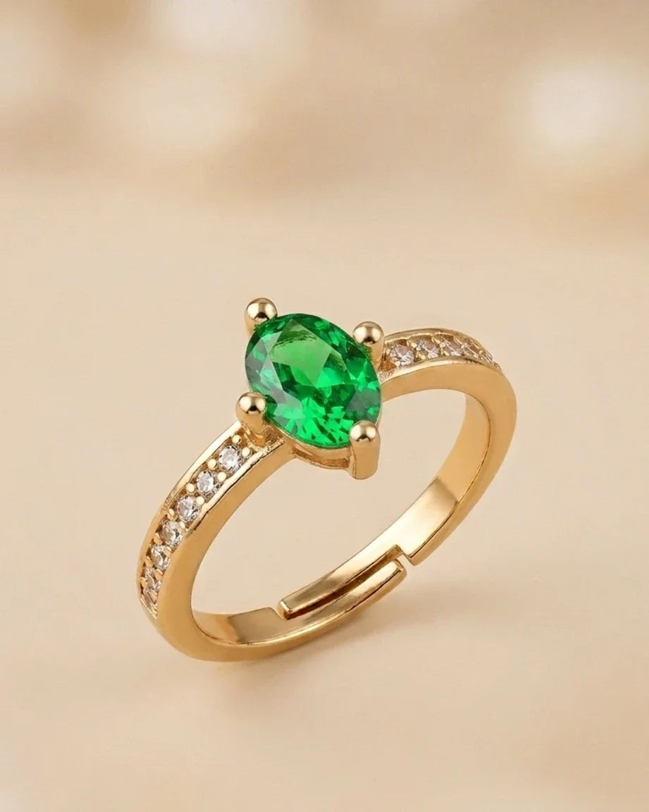 Gold ring with a green gemstone on a beige background