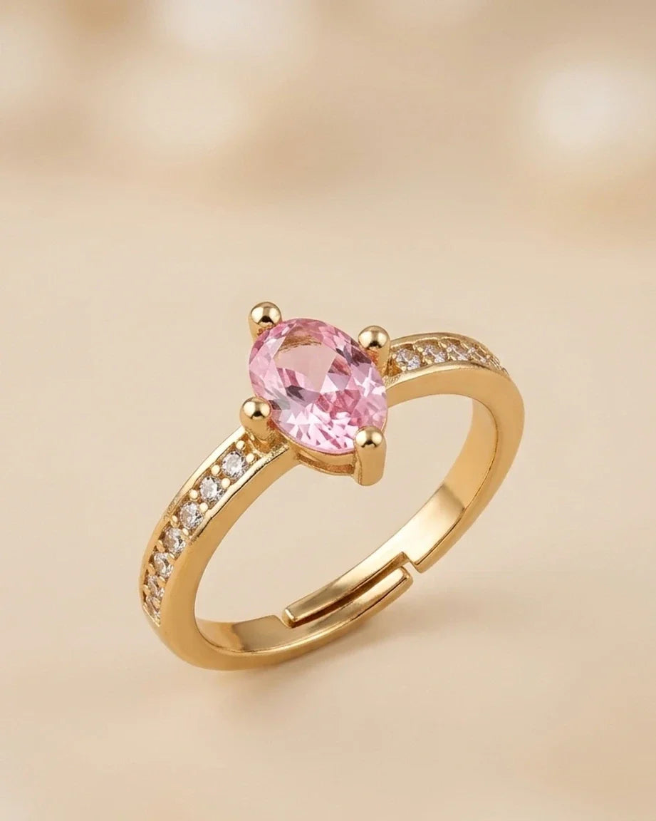 Gold ring with a pink gemstone on a beige background