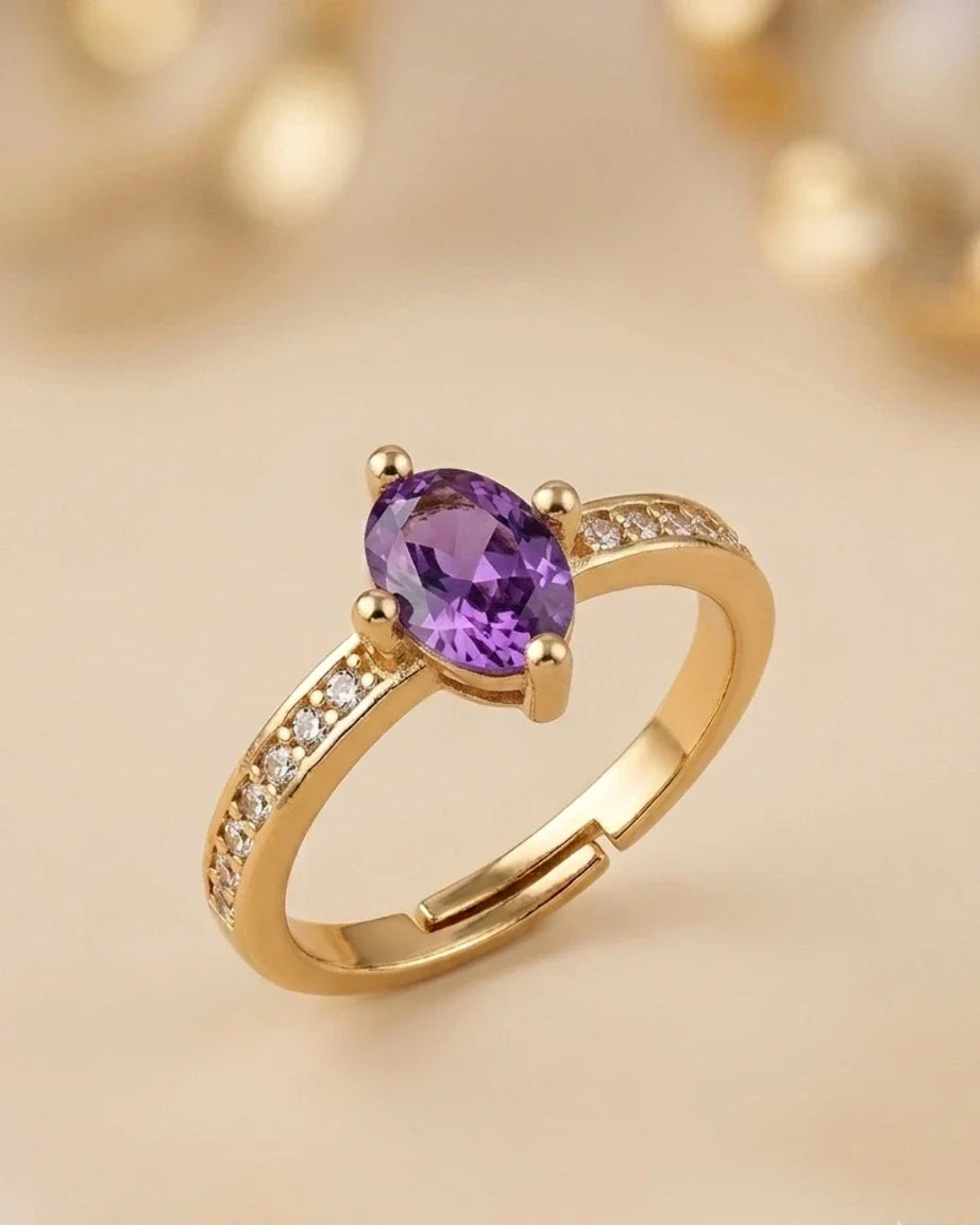 Gold ring with a purple gemstone on a beige background