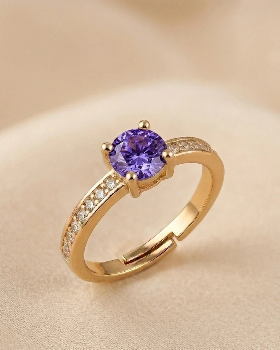 Gold ring with a purple gemstone on a beige background