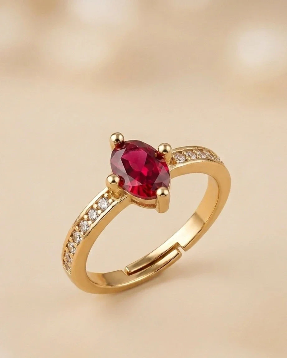 Gold ring with a red gemstone on a beige background