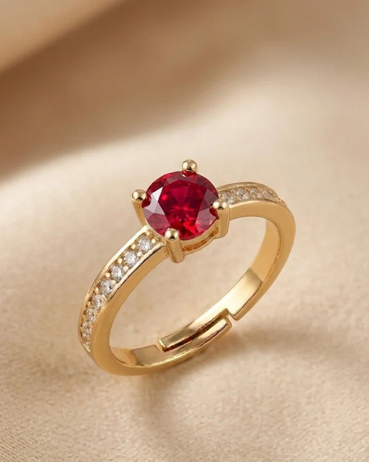 Gold ring with a red gemstone on a beige background