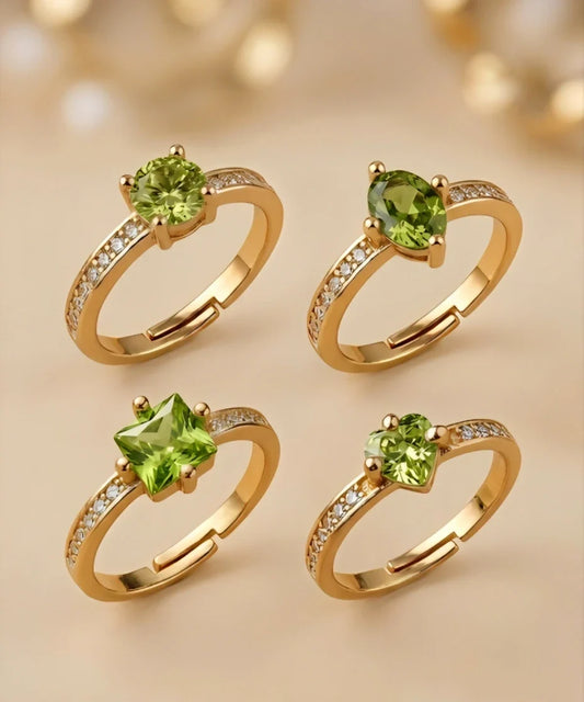 Four gold rings with green gemstones on a beige background