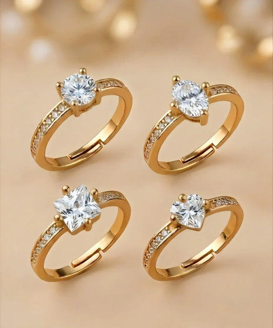 Four gold rings with diamond stones on a beige background